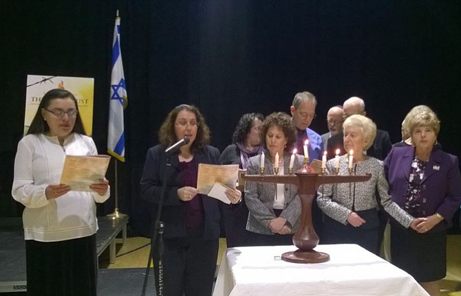 Participants of the Yom Ha’Shoah service May 1 in the Jewish Community Center gymnasium prepare to light the fifth candle on the menorah for the children of Holocaust survivors and pledge to commemorate, educate and forever remember the ways their parents suffered.  Front, from left to right:  Virginia Community Choir singer Judith Fogel, Rabbi Michelle “Mina” Goldsmith from Herndon synagogue Congregation Beth Emeth, Lesley Weiss – who lit the candle for her mother and Holocaust survivor Irene Weiss -- and Myra Brown Gondos.
