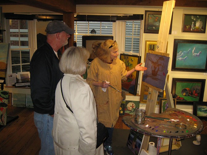 Artist Judith St. Ledger-Roty discusses her painting with guests at the First Friday Art Walk in the Village in Great Falls. 