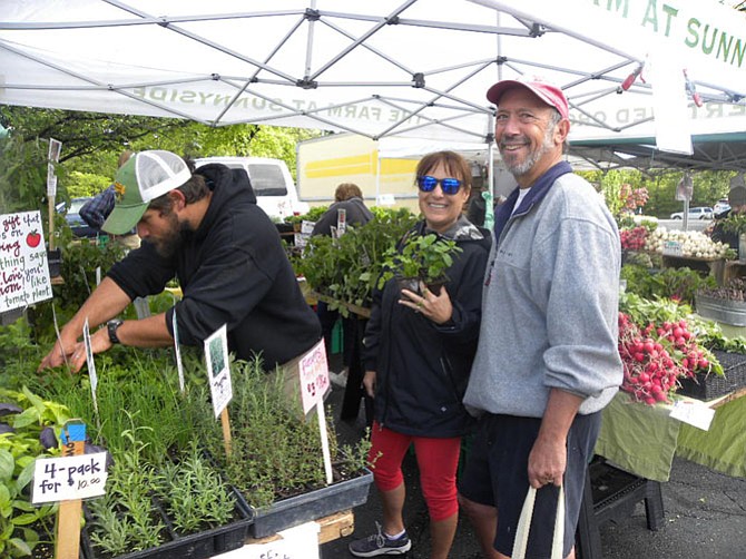 Casey Gustawarow (left) of The Farm at Sunnyside helps Allan and Barbara Ratner, of Reston, choose herbs on the opening day of the Reston Farmers Market on Saturday, May 7.
