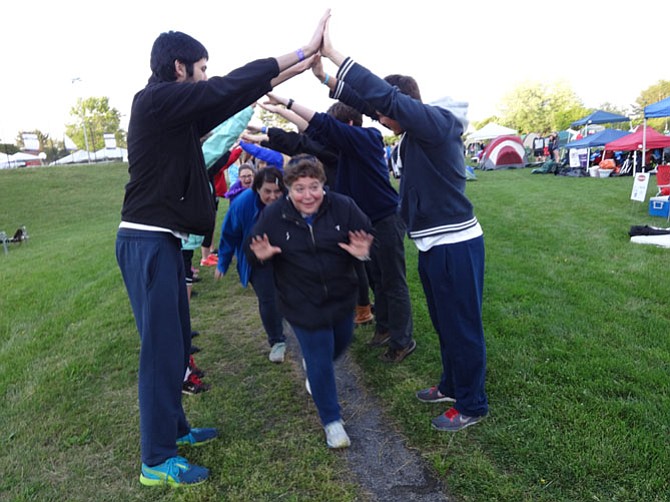 Beaming cancer survivors run under the arms of their caretakers and Relay volunteers.

