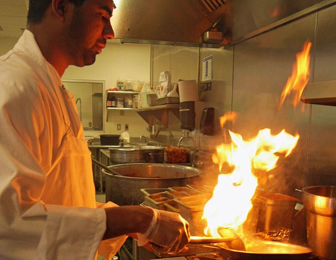 London Curry House Chef Naina Mohammed flames fennel geek, a dried chili and chopped tomatoes to give his curry dish a smoked flavor.
