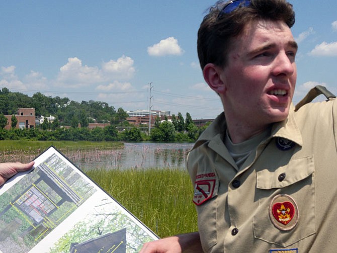 Thomas Pollack consults a diagram of the kiosk that he is supervising as his Eagle Scout project for Troop 135. He points to the top of the partially-finished kiosk where the roof will sit as the final step. The kiosk is located where the new Four Mile Run Wetlands Trail and Bike Trail meet in Four Mile Run Park.
