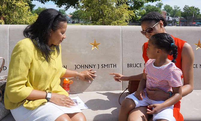 Arlisa Smith, left, sits by the name of her brother, Army Spc. Johnny Smith, with daughter Victoria Polite and granddaughter Brooke Robinson, 3,  prior to the start of the Memorial Day ceremony May 30 at the Capt. Rocky Versace Plaza and Vietnam Veterans Memorial.
