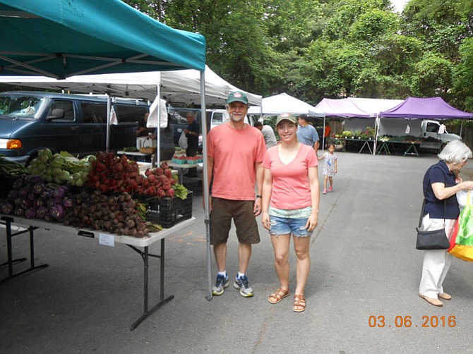 Farmers Market Manager Bob Baldwin and Market Coordinator Chelsea Roseberry near one vendor's produce section.
