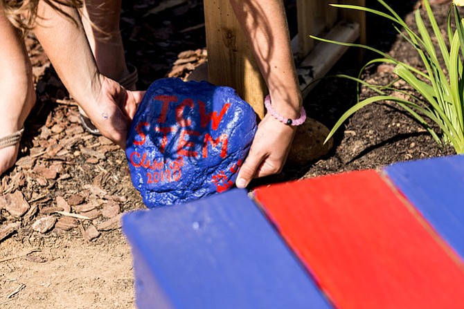 A ninth grade Minnie Howard student places a rock which they painted back in the garden. The painted rock was originally removed from the garden area when renovations began.
