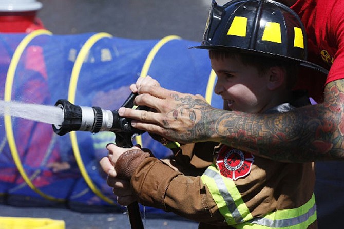 A young boy practices his skills as a firefighter at the 2016 Celebrate Fairfax.
