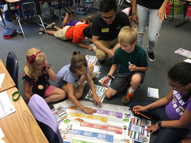 As part of the fourth grade “JA Our Region” module, PwC intern Troy Ruan helps fourth graders, from left, Anna Claire Sheehan, Kelly Via, Drake Thien, and Jaelyn Tappan understand the regional natural, human and capital resources entrepreneurs use to provide goods and services for their communities and recognize the knowledge, skills and abilities an entrepreneur uses to build a successful business.
