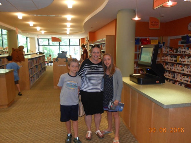 Stacey Smouse (center) and her two children, Hayden and Hannah, check out books for the Summer Reading Challenge.
