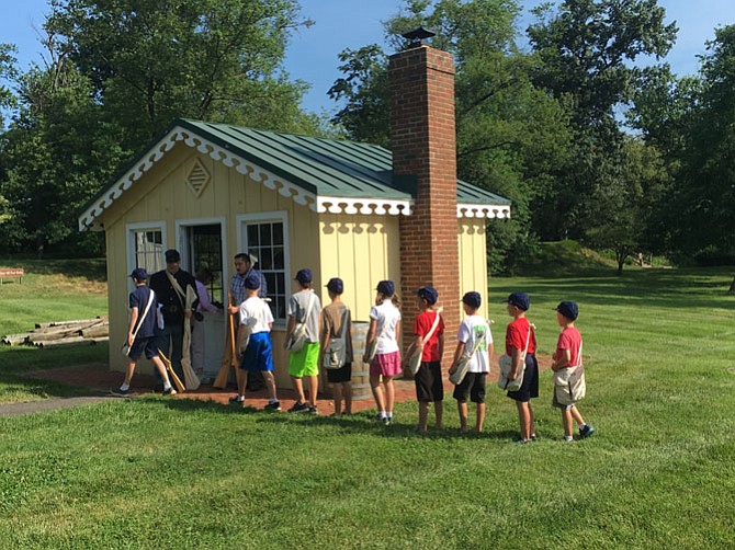 Youths line up tallest to shortest, as a real company of soldiers would fall in, to receive their prop muskets at Fort Ward’s Civil War Kid’s Drill Day. 
