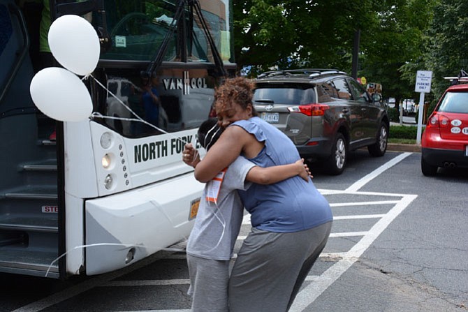 Fresh Air Fund family host Adriana Glenn (right) of Fairfax hugs her returning visitor Eric Galicia after he gets off the bus from New York City.