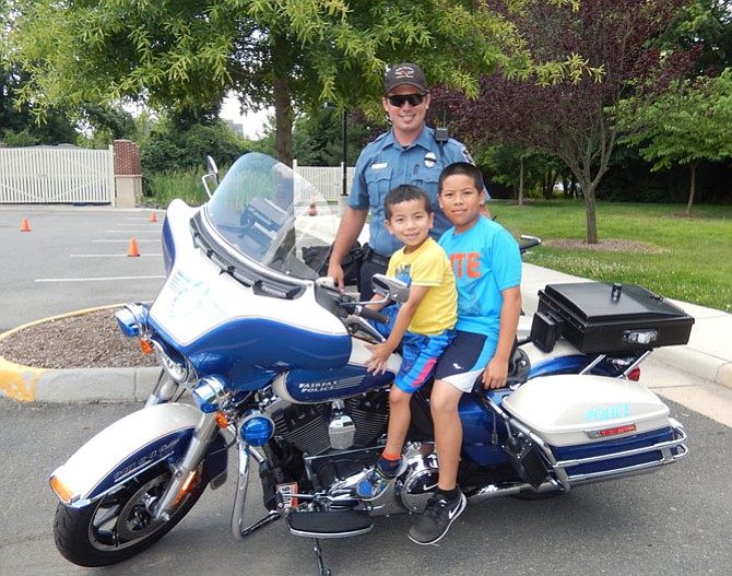 Brothers Billy Tran, 5, and Danny Tran, 10, sit on Officer Wade Brabble’s motorcycle.
