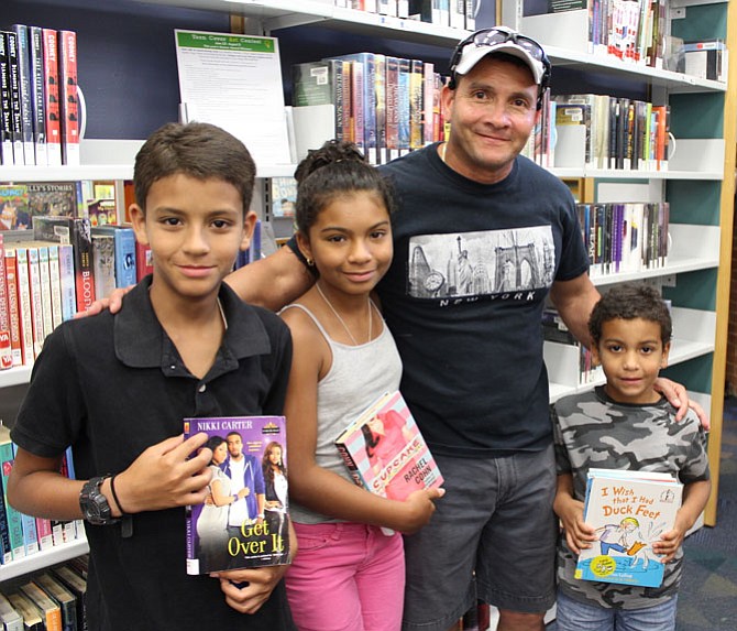 Residents of Lorton, father Alejandro Pabon  and children Alexander, 11, Alenette, 12, and Anthony, 7, picking out books for the summer challenge and the daily reading time they do each day with their father.

