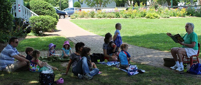 Darrell Pankratz of Vienna with 5-year-old twins William and Olivia who will attend Kindergarten at Vienna Elementary in the fall.  Tess Kelly, 4, and Maura Kelly, 6, have travelled from Rome, Italy to visit their grandmother Peggy Kelly in Vienna. Renee Stegman of Oakton with her daughter, age 3, and sons age 2 and 1.  Myrna Smith of Vienna with her granddaughter Rebecca Smith, 3, visiting for the summer. 
Kathy Tugendhat reads “Stop That Ball” to the children who have gathered for Vienna’s Summer Stories and Sprinklers.
