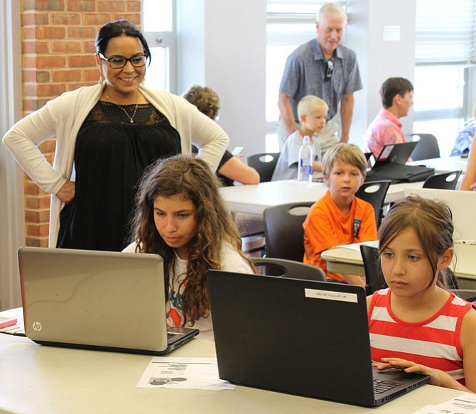 Ivelisse Figueroa, the assistant branch manager at Richard Byrd Library, watches the drag and drop coding project of Tabitah Press, 8, and sister Elissa Press, 10, residents of West Springfield, during the second session of Richard Byrd’s CoderDojo class.
