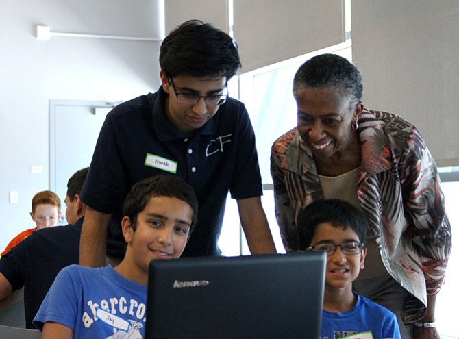 Students Jay Hemrajani, 11 (left), and Millen Chudasama, 10, show Pranab Krishnan and Supervisor Hudgins the code they were working on. The camp aimed to inspire creativity and innovation in science and technology.