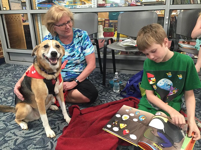 Jilly and owner Ina Watson (at left) listen to Raine Smith (right) read from an “Angry Birds” book.
