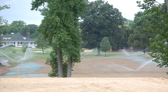 Irrigation sprinklers water small sprigs of Latitude 36 Bermuda grass in the tan area of the first-hole fairway. The blue material is mulch containing Fescue grass seed that was sprayed on disturbed areas of rough adjacent to the fairway.
