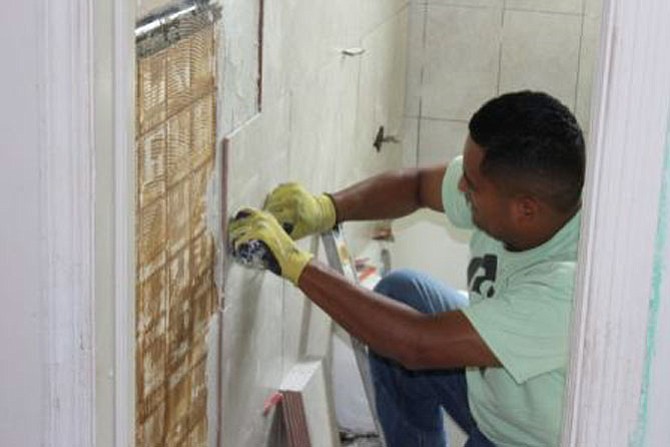 Eric Lopez, Community Lodgings' building engineer, replaces the bathroom tile as part of a complete bathroom renovation in a Community Lodgings affordable housing apartment. 