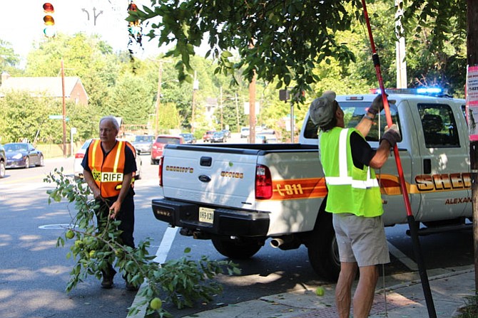 Sheriff Dana Lawhorne and a volunteer cut down branches that blocked the crosswalk signal at Commonwealth and Braddock.
