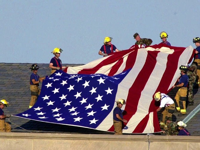 Lt. Jim Morris, far bottom right, and fellow firefighters from Alexandria and Fairfax County Fire and Rescue Station 11 join soldiers atop the Pentagon to unfurl an American flag during rescue and recovery efforts Sept. 12, 2001. Morris’s brother Seth died in the attacks on the World Trade Center.
