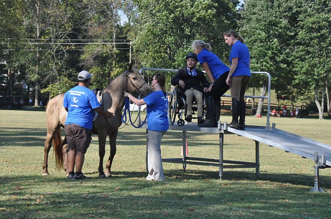 From left, Peter Colòn, Nicole Bass, Patti Towsley and Sarah Maceyak assist César Dulanto in mounting a horse at the 2015 Northern Virginia Therapeutic Riding Program Ride to Thrive fundraiser. 