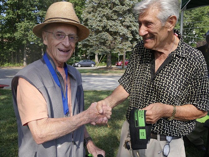 Nicholas Garito, Fairfax, shakes hands with his regular league bocce partner Henry Coletto after Coletto completes his bocce match in the 90-year old plus category in the Senior Olympics on Sept. 15. Garito says, “Henry turned 91 two weeks ago and instead of a cake I decided to celebrate with Oh Henry candy bars. I had to look all over to find them.” Colette says he put his in the freezer for the future. After the match they watch the other players and reminisce about the wars — World War II for Colette and Korean War for Garito.
