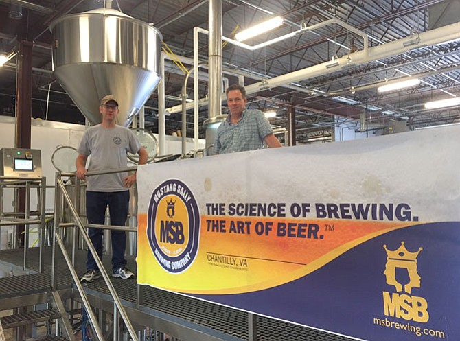 Mustang Sally Brewing Co.’s head brewer, Kenny Allen (left), and General Manager Dave Hennessey stand in front of the facility’s brewhouse, with the grist hopper and mash tun in the background.


