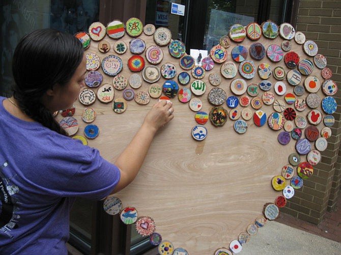 Ali Clements adds wood circles to One Heart, the collaborative community art work that will be displayed at the Reston Community Center. 