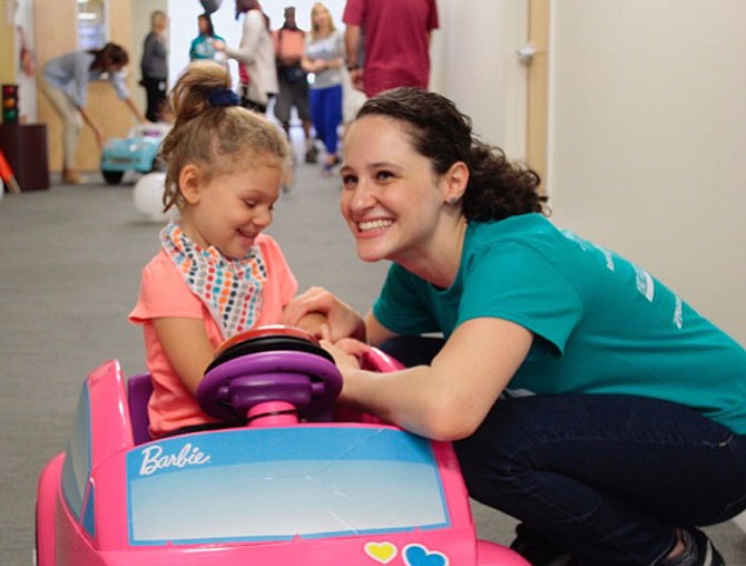 Five-year-old McKenna Card enjoys the Go Baby Go! car she received from Marymount University’s Department of Physical Therapy last year. She’s shown with Yuval Friedman of Good Beginnings.
