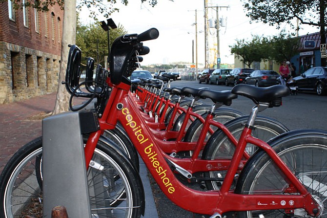 On the Potomac River, a ferry can be seen in the distance, just past the rental bikes and pedestrians in Old Town, exemplifying the variety of transportation available in Alexandria.
