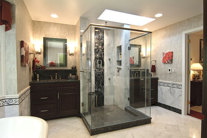 A glass enclosed walk-in shower accessible from two sides is tucked under a skylight.
