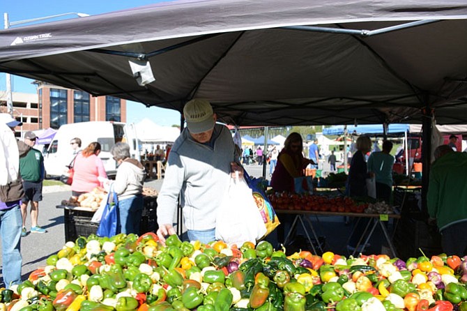 Zoran Duric of Fairfax chooses among a vibrant assortment of peppers from Santa Cruz Produce in Montross, Va. at the Burke Farmers Market on Oct. 15.