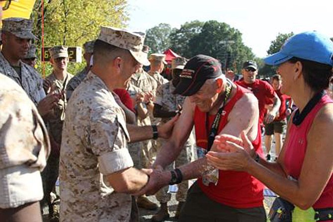 Al Richmond, center, is congratulated  by Quantico base commander Col. Joseph M. Murray after completing his 41st consecutive Marine Corps Marathon Oct. 30 in Arlington. The 77-year-old Maywood resident is the only individual to complete every MCM since its inception in 1976. He completed the course in 6:39:47.