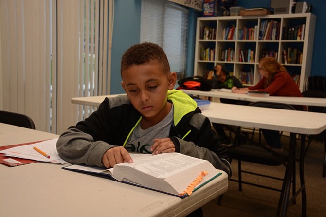 On a weekday afternoon, young Fairfax resident Demetrius Dowling works independently on an extra math word problem. 
