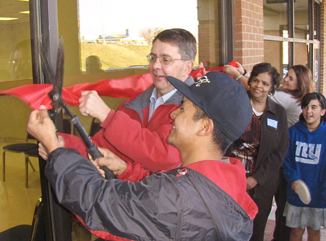 On Dec. 3, 2011, former Sully District Supervisor Michael Frey and worker Miki Carrillo (in hat) cut the ribbon on the center’s door together.