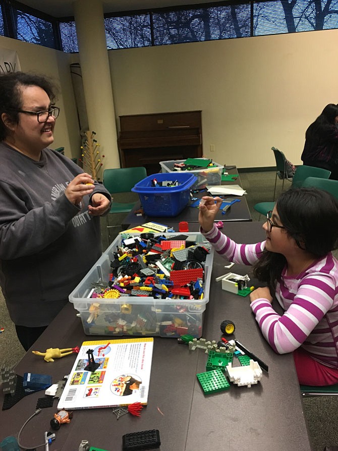 Potomac Library volunteer Rachael Mazzi smiles as Ana Velasquez, 10, shows her just the Lego she needed to finish her project. The library hosted a time of open Lego building on Monday.