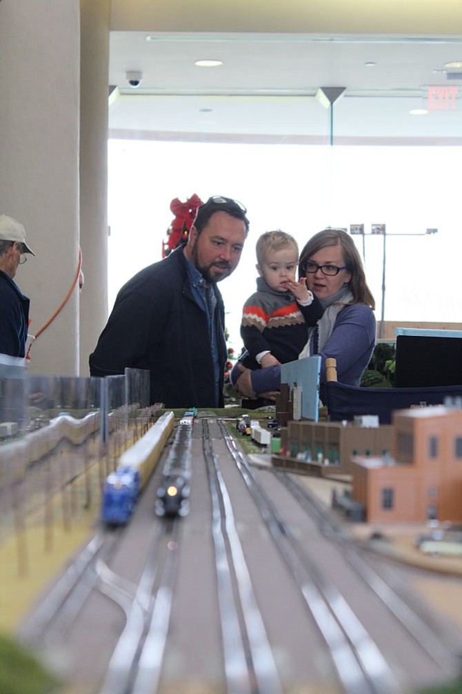 Martin Juenge, Max Juenge, 20 months, and Magda Juenge watch trains go down the tracks in a display by the Northern Virginia NTRAK, Inc. in the Herndon Municipal Center.