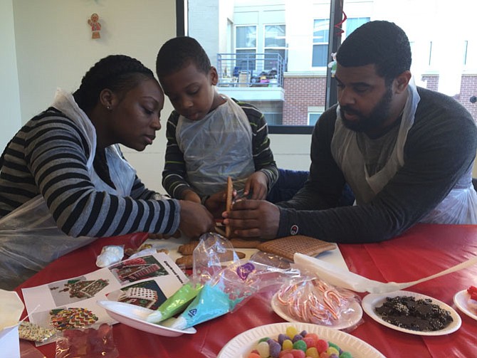Regina Brooks (left), Brian-Kobe Brooks (middle), and Brian Brooks (right) work on a gingerbread house together. Regina Brooks said her family has gone to the event for three years: “We love working together on this. It’s become a family tradition.” 