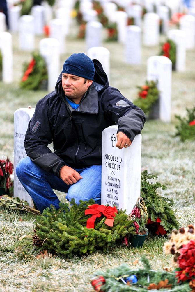 Navy SEAL and Medal of Honor recipient Ed Byers kneels next to the headstone of Nicolas Checque, a friend who was killed in 2012 in the same fight where Byers earned his Medal of Honor. Byers joined volunteers from Wreaths Across America Dec. 17 in placing more than 245,000 wreaths to honor the veterans buried at Arlington National Cemetery.