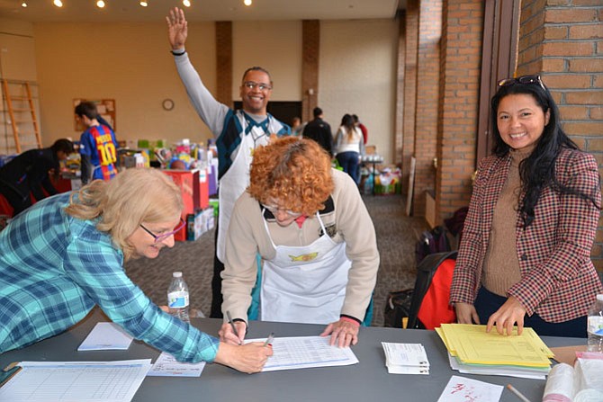 Making a list and checking it twice are FISH volunteers, from left: Ellen Scheinfeld, James Bell of Life Ticket Church – waving in the back row – Susan Markel, and Gracy Olmeda, another volunteer from Life Ticket Church.
