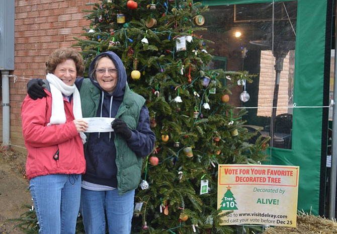 The Del Ray Business Association's Pat Miller presents ALIVE! executive director Diane Charles with a $500 check, the Alexandria non-profit's prize for winning the 2016 Del Ray Tree Decorating Contest. The ALIVE! tree featured food-themed decorations, spotlighting their work as the largest private safety net for the needy in the City of Alexandria. Twelve Alexandria-based non-profits participated in the annual contest, which was decided by a public online vote.
