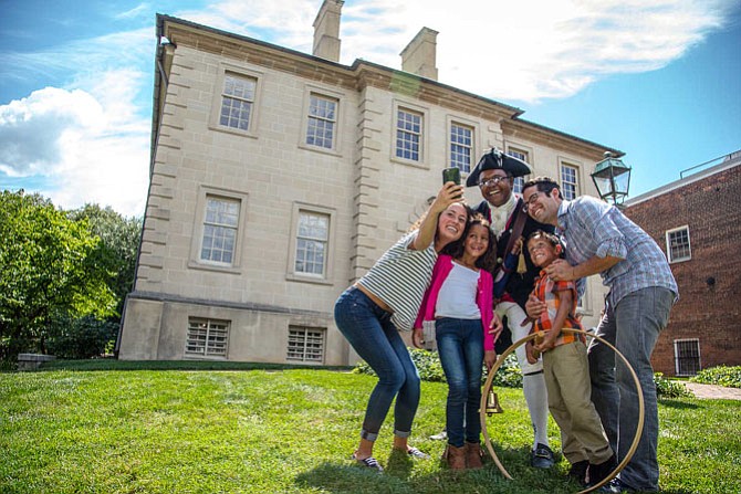 Family takes a selfie with Town Crier Ben Fiore-Walker outside the Carlyle House.