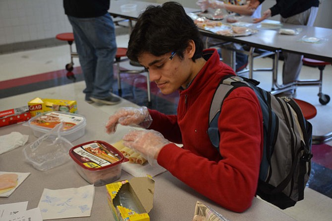 A member of the Class of 2017 rolls lunchmeat and cheese together to create sandwiches.
