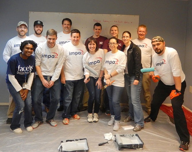 Excella Consulting employees take a painting break to pose with FACETS’ D’Ivonne Holman (in blue shirt).
