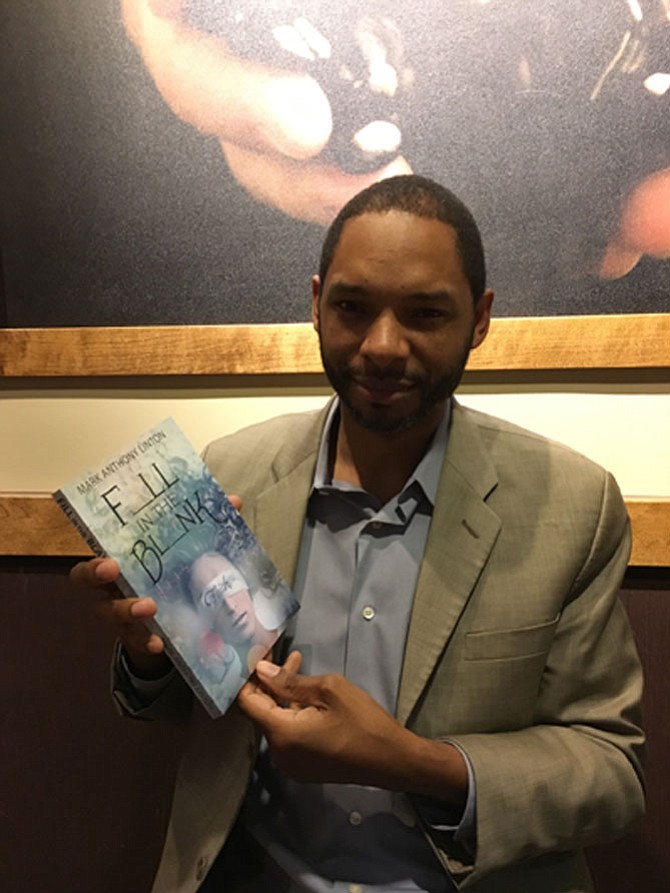 Potomac resident Mark Anthony Linton shows a copy of his first book, “F_LL in the BL_NK,” about his quest to become a “Wheel of Fortune” contestant.
