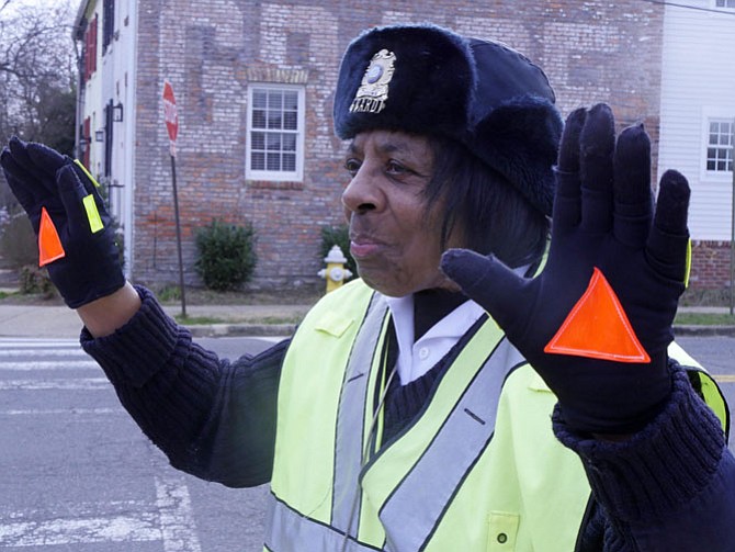 Cora Reed raises her hands high in the air to stop cars from four directions at the corner of S. Asaph and Gibbon outside Lyles-Crouch Elementary School.  