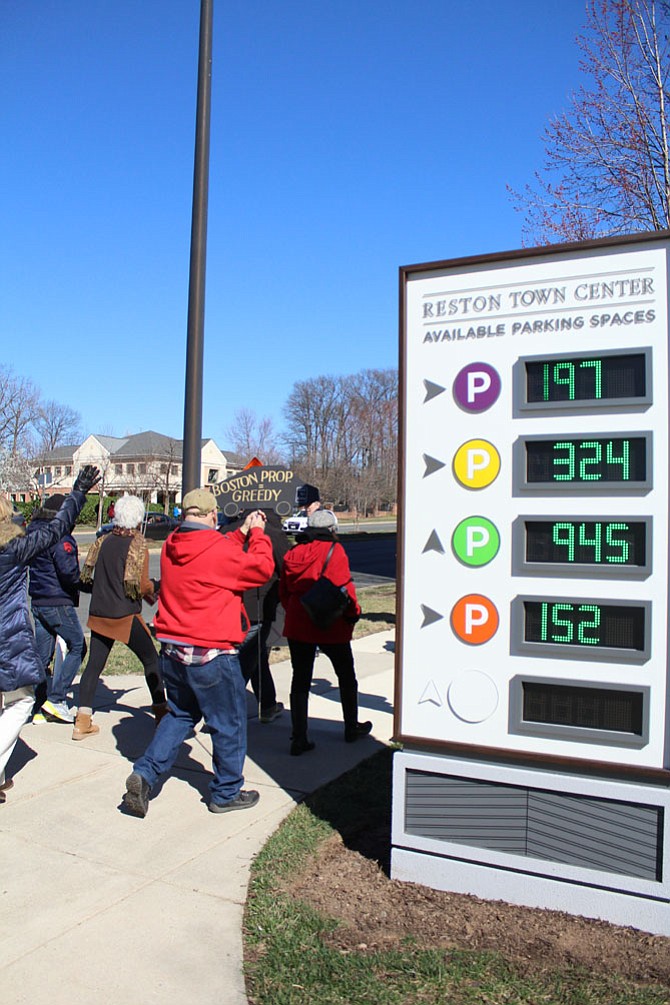 Protesters march past a Reston Town Center parking garage sign that displayed more than 1,600 vacant parking spaces in the garages—which are free on Saturdays and Sundays.