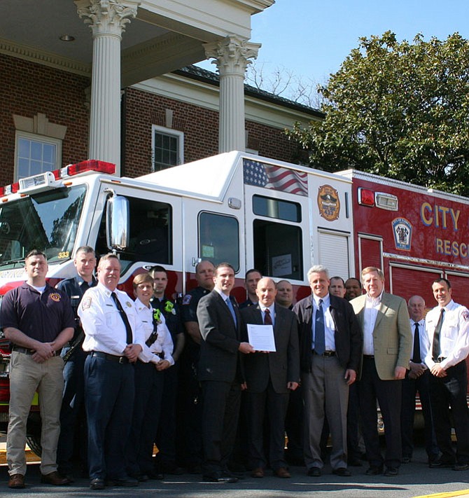 Outside City Hall, City Councilman Jon Stehle presents the letter notifying the City Fire Department about its top fire-protection rating. Also pictured are Fire Department personnel, including Chief John O’Neal (white shirt, far left) and City Manager Bob Sisson (tan jacket, on right).