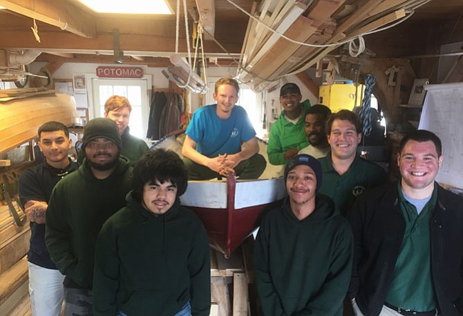 Surrounded by fellow apprentices and staff, Jay Helinksi, center, poses atop his hand crafted boat Feb. 28 to celebrate graduation from the Alexandria Seaport Foundation’s apprentice program.