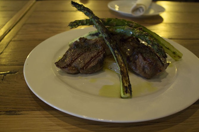 Tender lamb chops are served with potatoes and asparagus.